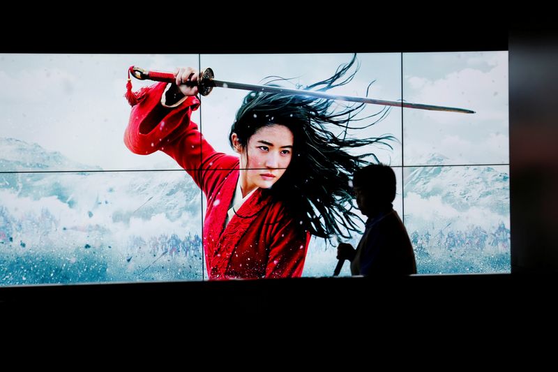 &copy; Reuters. FILE PHOTO: Cleaner walks past screens promoting Disney&apos;s movie &quot;Mulan&quot; as the film opens in China, at a cinema in Beijing