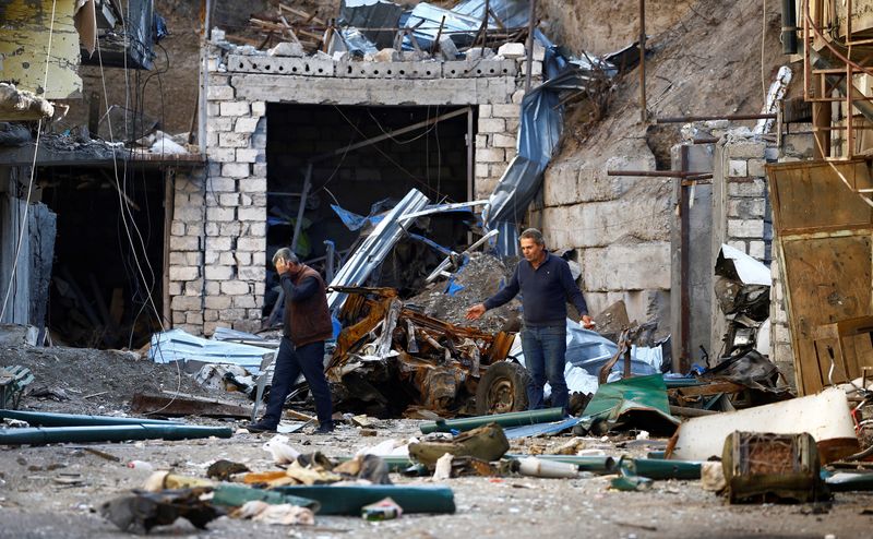 © Reuters. FILE PHOTO: Men are seen among the ruins after recent shelling during the military conflict over the breakaway region of Nagorno-Karabakh, in Stepanakert