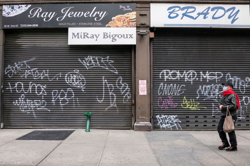 © Reuters. FILE PHOTO: A man wearing a mask walks past shuttered businesses on Broadway