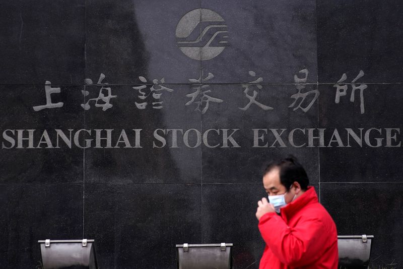 &copy; Reuters. Un uomo con indosso la mascherina passa accanto alla sede della Borsa di Shanghai, Cina, durante l&apos;epidemia di coronavirus
