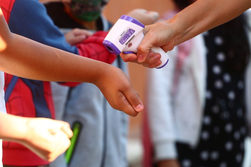 © Reuters. Pupils have their temperature checked before entering on the first day of school amid the coronavirus disease (COVID-19) outbreak in Madrid