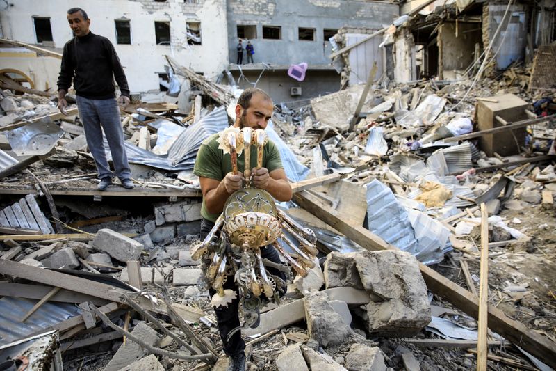 &copy; Reuters. Homens caminham por destroços de local atingido durante conflitos na cidade de Ganja, na região de Nagorno-Karabakh