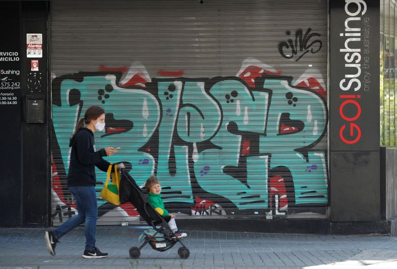 &copy; Reuters. Una mujer camina empujando un carricoche junto a un restaurante cerrado en Barcelona