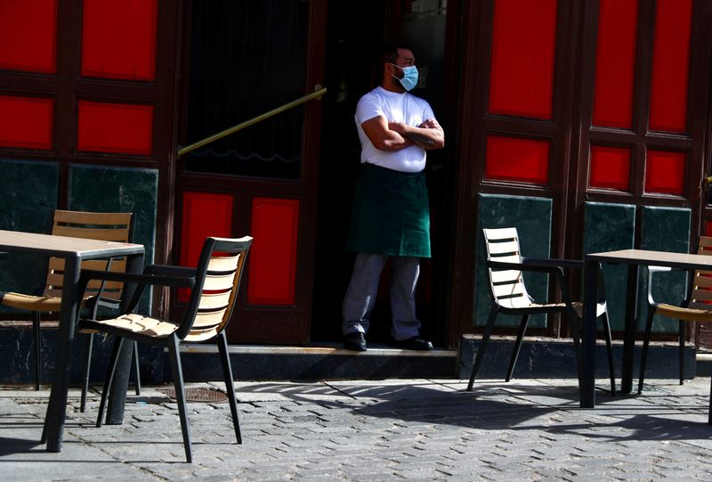 &copy; Reuters. FOTO DE ARCHIVO: Un camarero con mascarilla protectora espera a los clientes en su terraza en medio del brote de coronavirus en Madrid. 1 de octubre 2020.