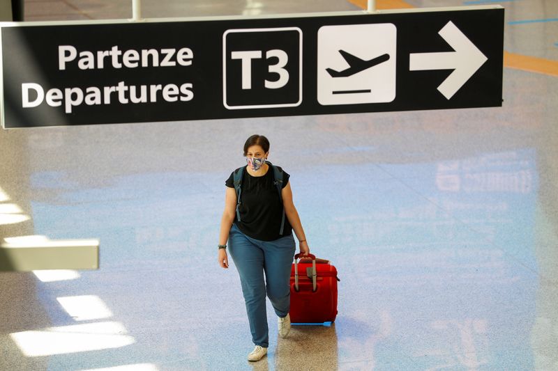 &copy; Reuters. Una donna con una valigia e una maschera presso l&apos;aeroporto di Roma Fiumicino