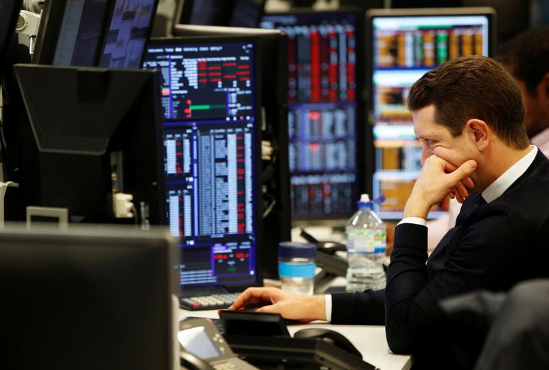 © Reuters. Traders work at their desks whilst screens show market data at CMC Markets in London