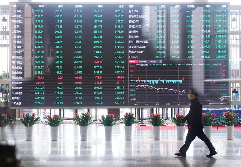 &copy; Reuters. Un uomo con addosso una mascherina attraversa la sede della Borsa di Shanghai, 28 febbraio 2020