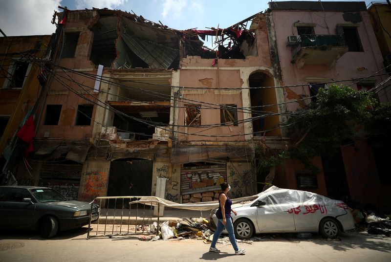 © Reuters. FOTO DE ARCHIVO: Rita Faraj Oghlo, de 31 años, pasa frente a un edificio dañado en Beirut