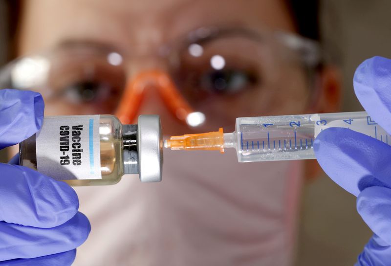 &copy; Reuters. FILE PHOTO: A woman holds a small bottle labeled with a &quot;Vaccine COVID-19&quot; sticker and a medical syringe in this illustration