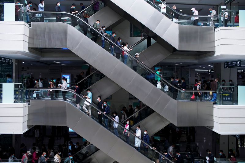&copy; Reuters. People wearing face masks stand on escalators at a hospital