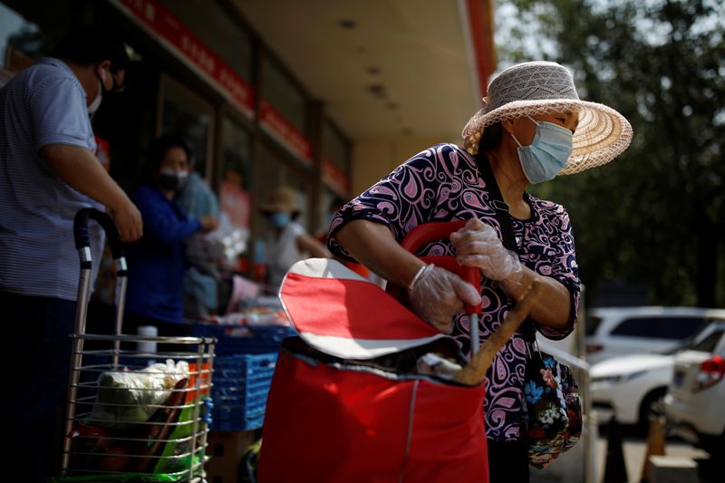 &copy; Reuters. Woman holds a trolley outside a supermarket in Beijing