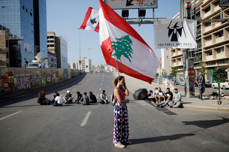 &copy; Reuters. FILE PHOTO: A woman holds a Lebanese flag as she stands at a roadblock during ongoing anti-government protests in Beirut