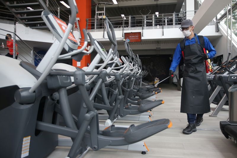 &copy; Reuters. Homem com traje de proteção desinfecta equipamentos de ginástica em academia em Bogotá, na Colômbia, em meio à pandemia de coronavírus