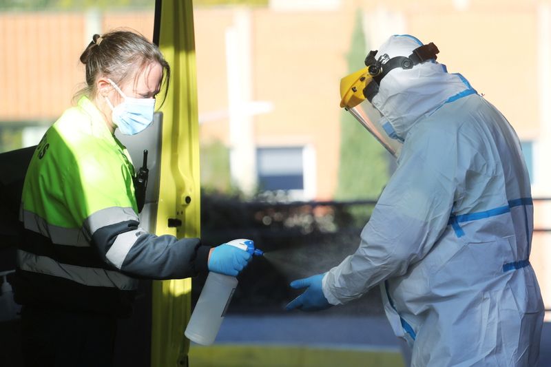 &copy; Reuters. FILE PHOTO: An ambulance worker wearing a full personal protective equipment (PPE) is disinfected by a collage in Leganes