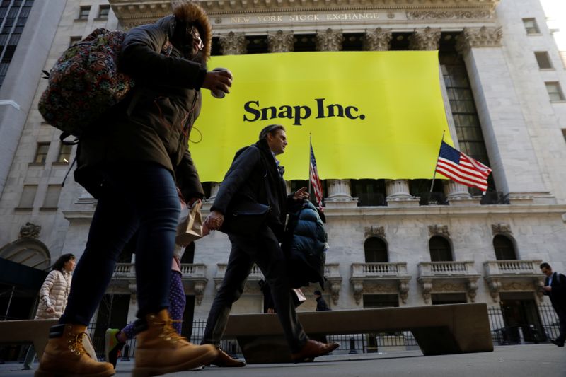 &copy; Reuters. Pedestrians walk past the front of the New York Stock Exchange (NYSE) with a Snap Inc. logo hung on the front of it shortly before the company&apos;s IPO in New York