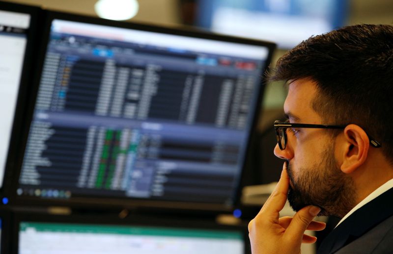 © Reuters. Trader works at his desk whilst screens show market data at CMC Markets in London