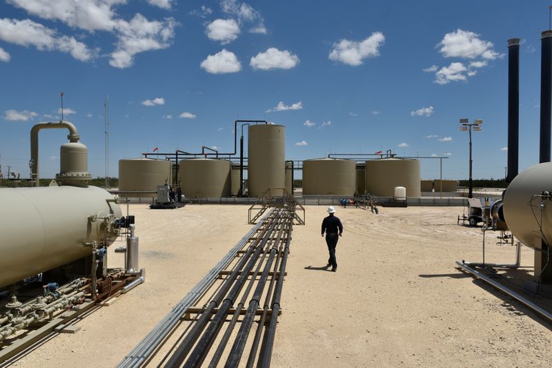 © Reuters. Lease Operator Jeremy Jay walks through an oil production facility owned by Parsley Energy in the Permian Basin near Midland