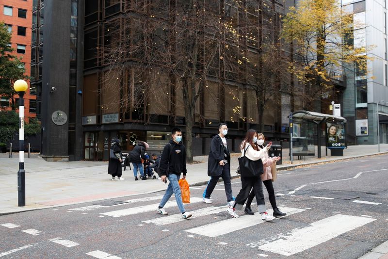 &copy; Reuters. Pessoas usando máscaras atravessam rua em Manchester