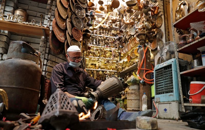 &copy; Reuters. A vendor works on a copper item to be sold in a shop in Baghdad