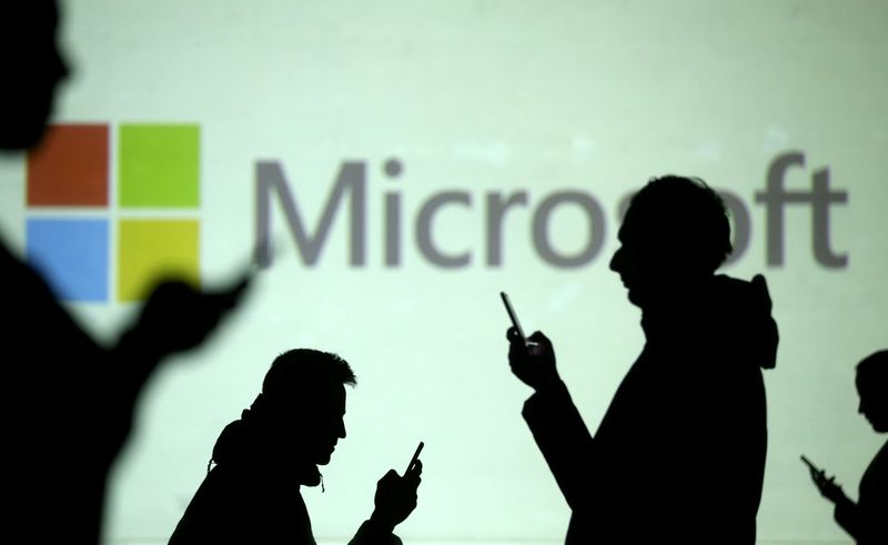 © Reuters. FILE PHOTO: FILE PHOTO: Silhouettes of mobile users are seen next to a screen projection of Microsoft logo in this picture illustration
