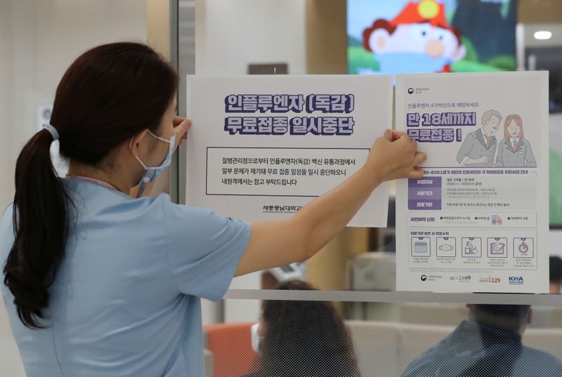 &copy; Reuters. FOTO DE ARCHIVO. Una trabajadora de la salud adjunta un aviso de suspensión de los programas de vacunación contra la influenza en la entrada de un hospital en Sejong, Corea del Sur