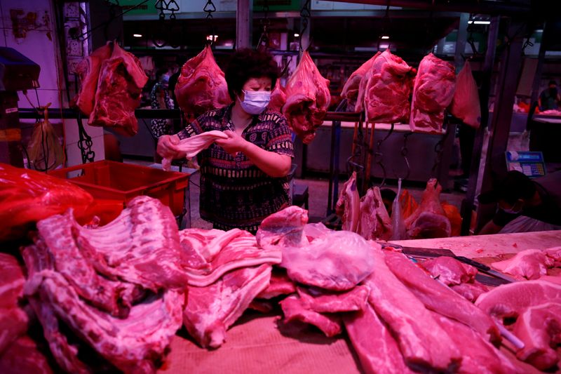 © Reuters. Vendedora prepara cortes de carne suína em mercado em Pequim, China