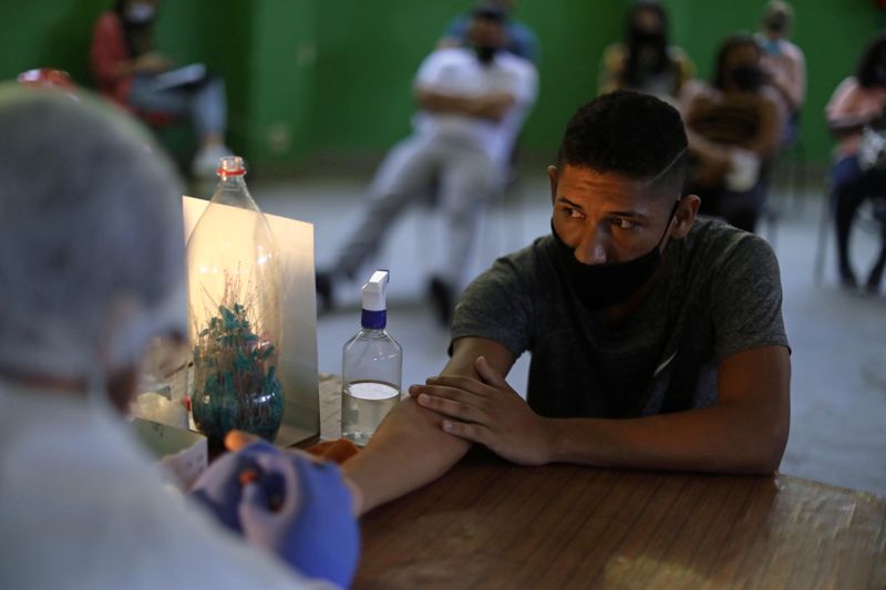 &copy; Reuters. Homem é submetido a coleta de sangue para teste da Covid-19 em favela do Rio de Janeiro