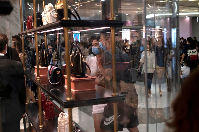 &copy; Reuters. FILE PHOTO: Customers wearing face masks following the coronavirus disease (COVID-19) outbreak, look at the products at a Gucci store, at the Sanya International Duty-Free Shopping Complex, in Sanya
