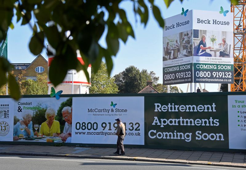 &copy; Reuters. FILE PHOTO:  A man walks past hoardings advertising retirement apartments currently being built behind on site by McCarthy &amp; Stone in London, Britain