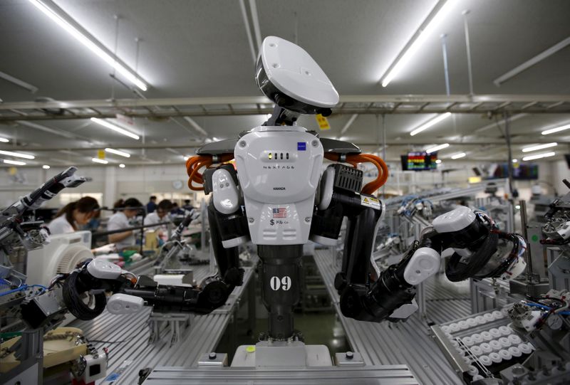 © Reuters. FILE PHOTO: A humanoid robot works side by side with employees in the assembly line at a factory of Glory Ltd., a manufacturer of automatic change dispensers, in Kazo, north of Tokyo