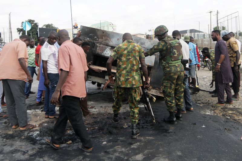 &copy; Reuters. Miembros del ejército se suman a civiles para retirar un generador eléctrico quemado desde una calle en Ikeja