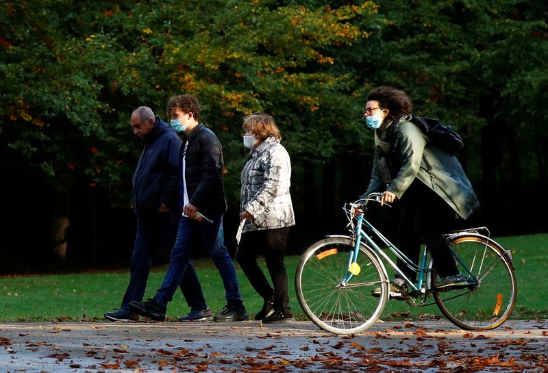 &copy; Reuters. FOTO DE ARCHIVO: Una ciclista pasa junto a varias personas con mascarilla en Bruselas