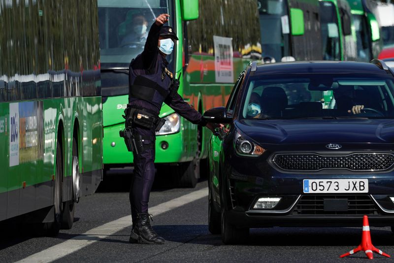&copy; Reuters. FOTO DE ARCHIVO: Un agente de la Policía Nacional con una mascarilla se dirige a los ocupantes de un vechículo en Madrid