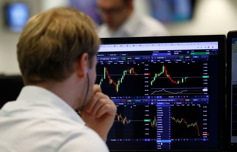 &copy; Reuters. FILE PHOTO:  A financial trader works at their desk at CMC Markets in the City of London