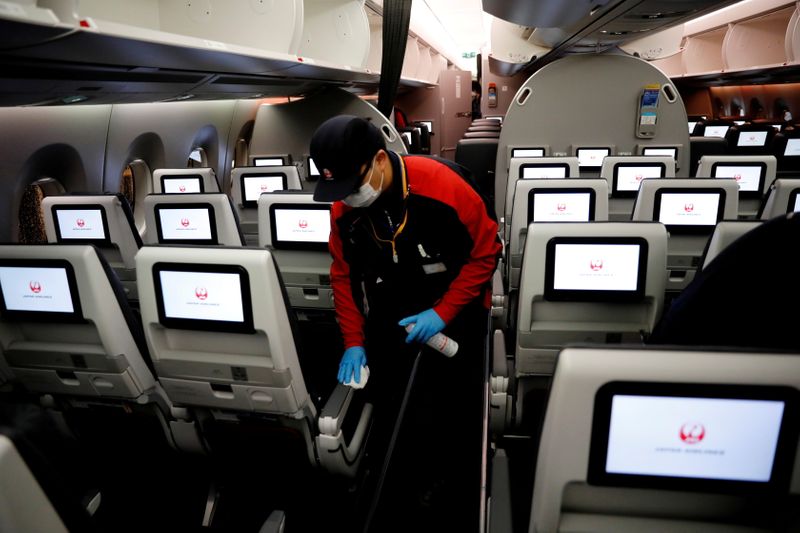 &copy; Reuters. FILE PHOTO: A staff member of Japan Airlines wearing a protective face mask and gloves cleans the cabin of a plane which performed a domestic flight, amid the coronavirus disease (COVID-19) outbreak at Haneda airport in Tokyo