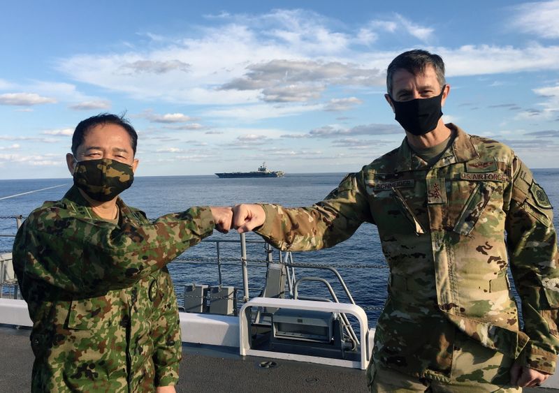 &copy; Reuters. General Kevin Schneider, comandante das forças dos EUA no Japão, e general Koji Yamazaki, principal comandante militar do Japáo, se cumprimentam a bordo do destróier JS Kaga no mar ao sul do Japão