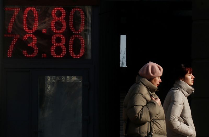 © Reuters. People walk past a board showing the currency exchange rates of the U.S. dollar against the Russian rouble in Moscow