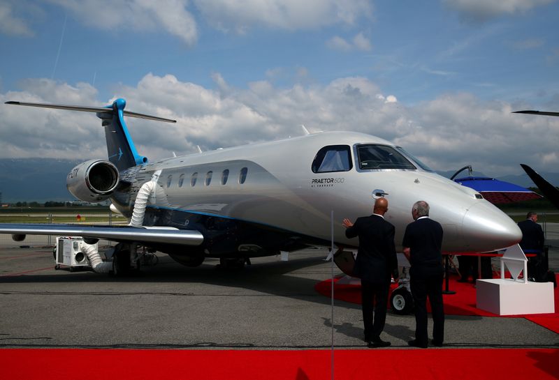 &copy; Reuters. FILE PHOTO: Visitors talk in front of the Praetor 600 aircraft on the Embraer stand in 2019 during the EBACE at Cointrin Airport in Geneva