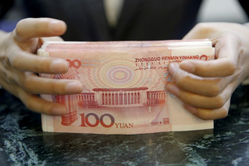 © Reuters. FILE PHOTO: A clerk of ICBC bank counts Chinese one hundred Yuan Banknotes as she poses for camera during a photo opportunity at its branch in Beijing