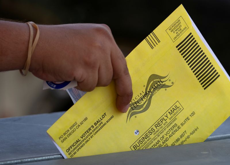 © Reuters. FILE PHOTO: An election worker places mail-in ballots into a voting box at a drive-through drop off location at the Registrar of Voters for San Diego County in San Diego, California