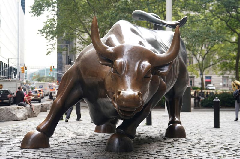 © Reuters. FILE PHOTO: People pose for a photo at the Charging Bull statue, also known as the Wall St. Bull, is pictured in the financial district