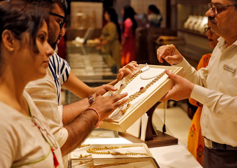 &copy; Reuters. FILE PHOTO:  A salesman shows a gold necklace to customers at a jewellery showroom in Ahmedabad