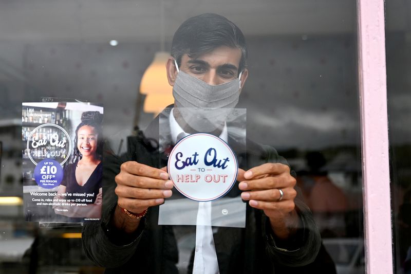 © Reuters. FILE PHOTO: Britain's Chancellor of the Exchequer Rishi Sunak, wearing a face mask, places a sticker as he meets with local business people during a visit to Rothesay, in the Isle of Bute, Scotland