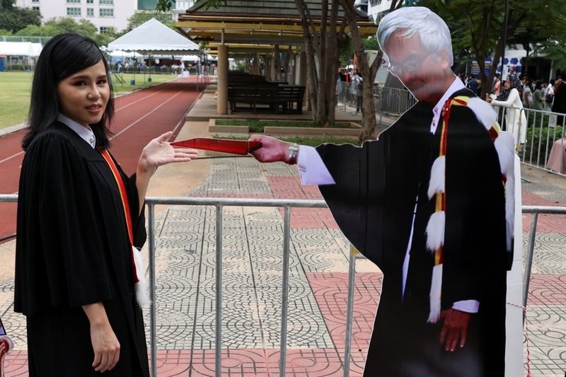 &copy; Reuters. A student stands next to a cardboard figure of Somsak Jeamteerasakul, an exiled Thai academic, before a graduation ceremony, which some students have boycotted because it is led by King Maha Vajiralongkorn, at Thammasat University in Bangkok