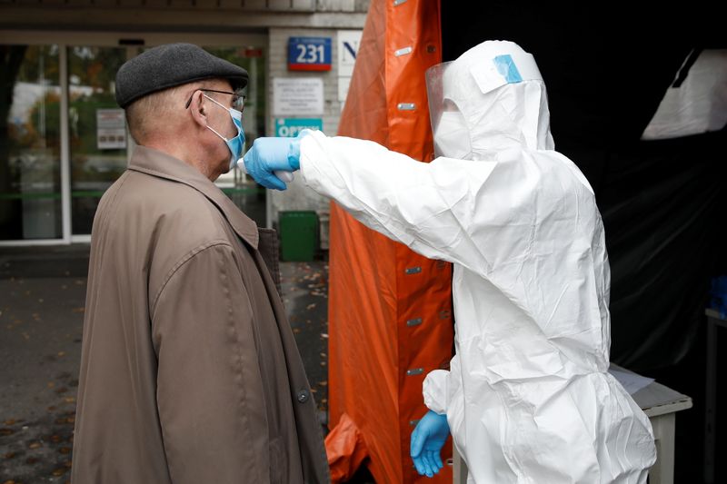 &copy; Reuters. A man in protective suit checks a man&apos;s temperature in Warsaw