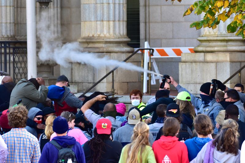 © Reuters. Law enforcement officers spray protesters shortly after a moment of silence during a Get Out The Vote march in Graham