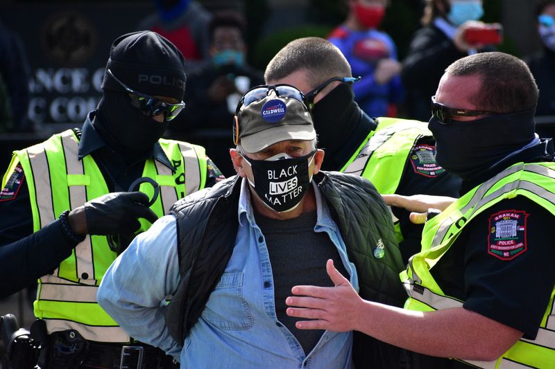 &copy; Reuters. A man is detained by Graham Police officers after a moment of silence during a Get Out The Vote march in Graham