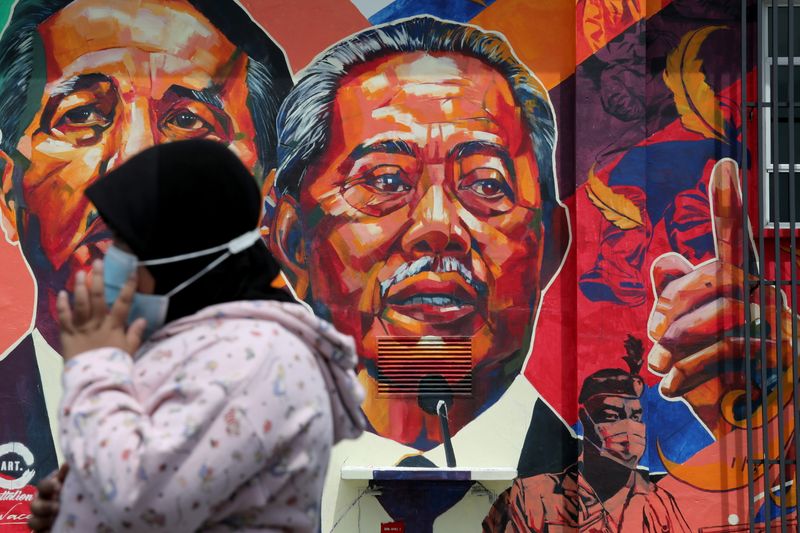 &copy; Reuters. A woman passes by a mural depicting Malaysia&apos;s Prime Minister Muhyiddin Yassin in Kuala Lumpur