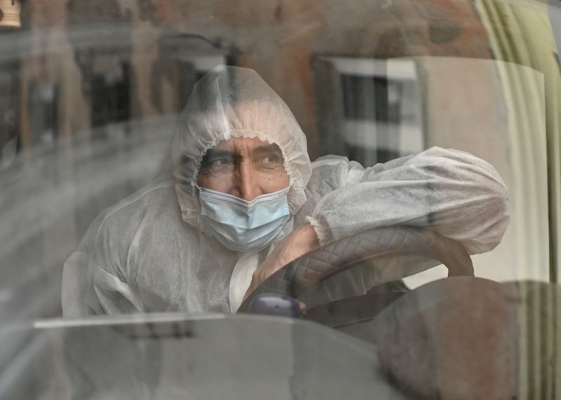 &copy; Reuters. A driver wearing personal protective equipment sits in an ambulance outside a hospital amid the coronavirus disease outbreak in Omsk