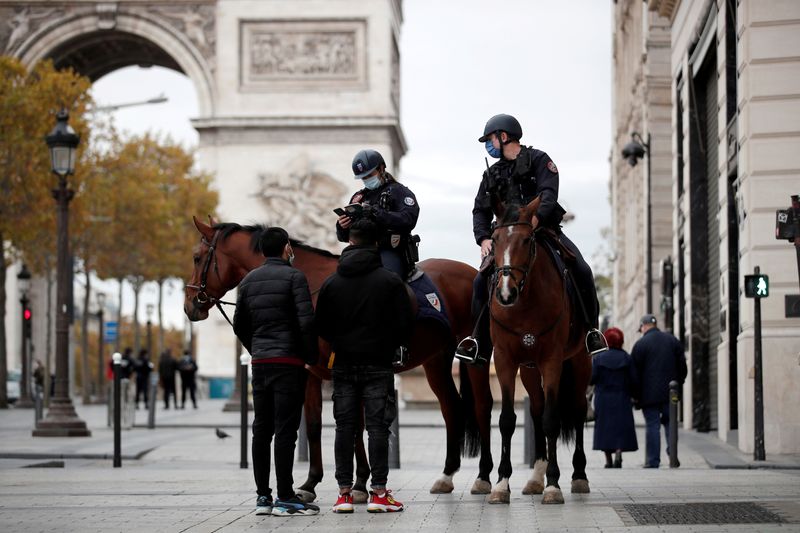 &copy; Reuters. Policiais montados a cavalo e com máscaras de proteção checam identidade de pessoa na avenida Champs Elysee, em Paris